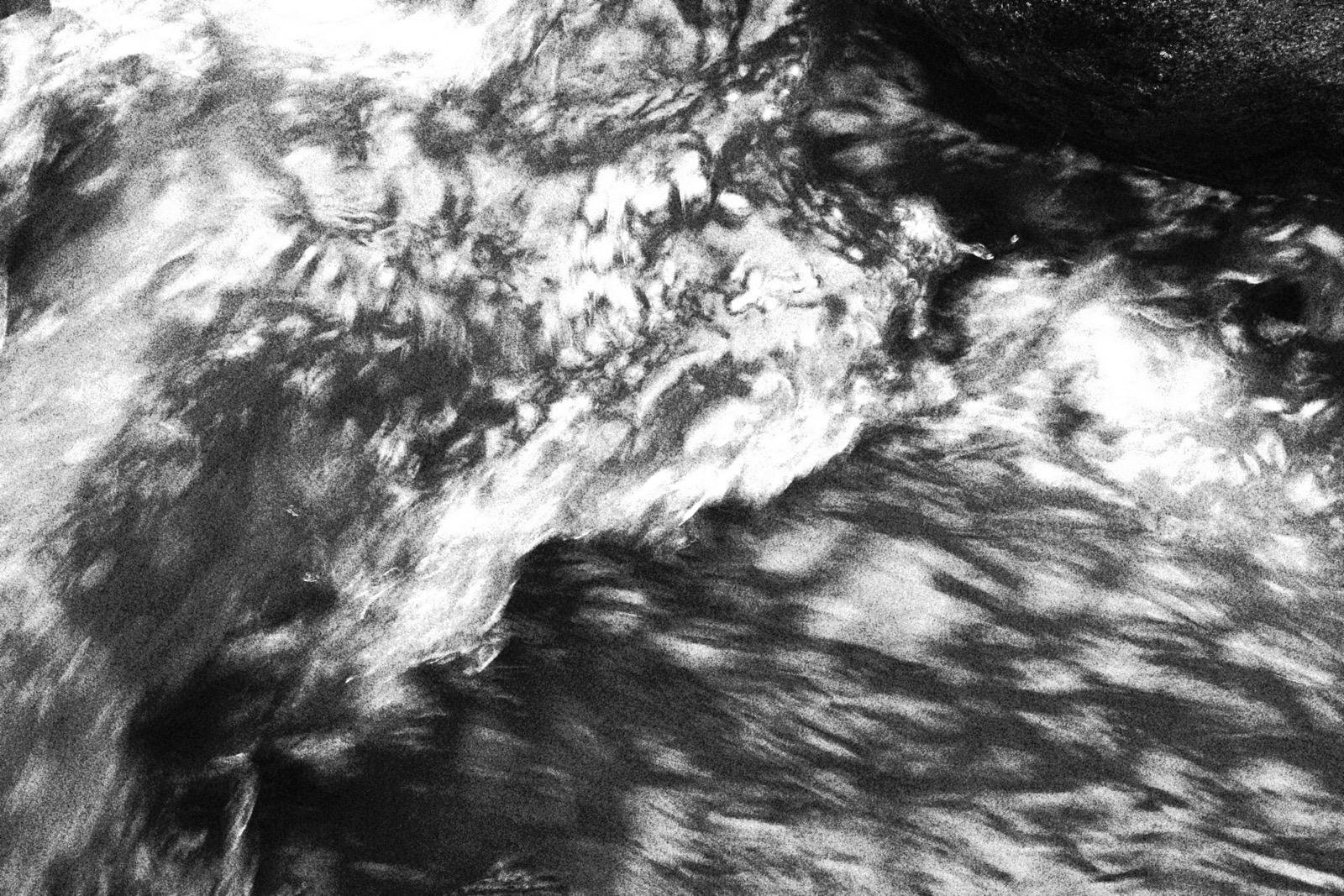 Pieza abstracta: agua de río en movimiento, en blanco y negro de alto contraste.